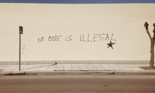 photo of graffiti that reads "No on is illegal" by Mike Guziuk