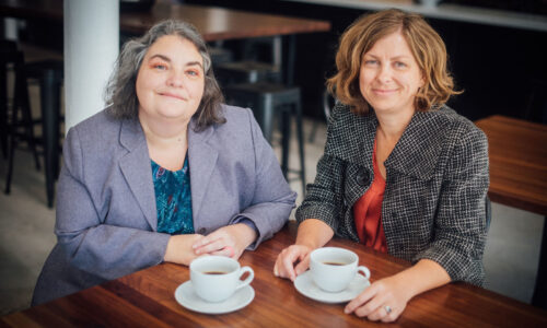 Kathleen and Leah smiling over a cup of coffee